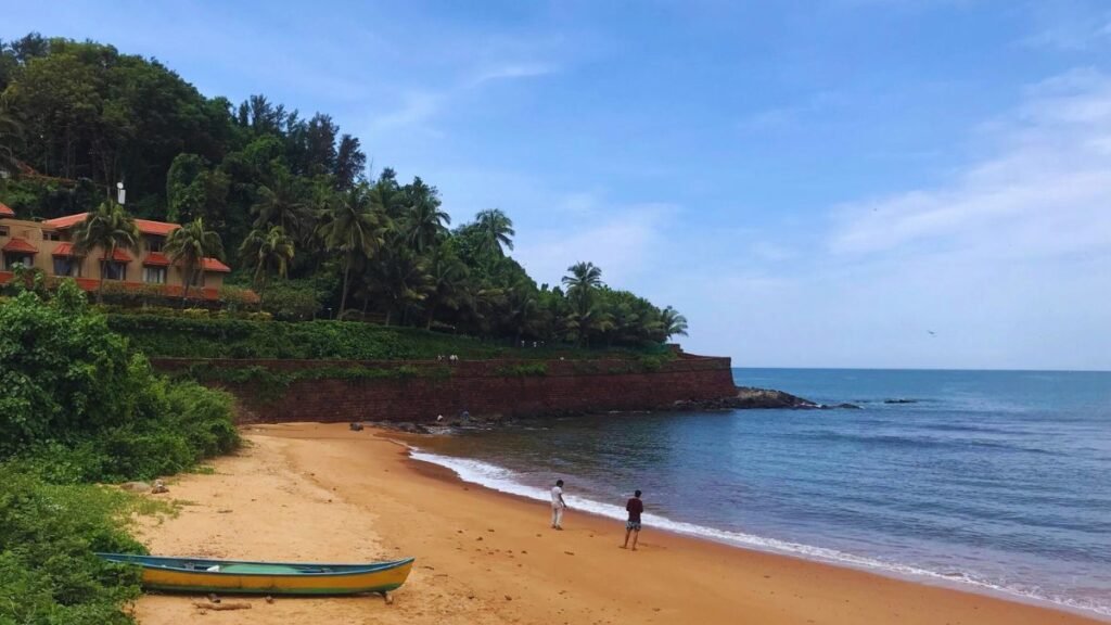 A view of Sinquerim beach with two people and boat in the backdrop