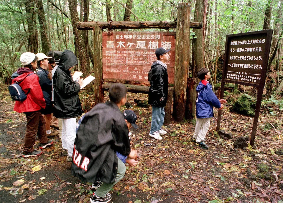 a group of children reading the signboard places at the entrance of the suicide forest in JAPAN